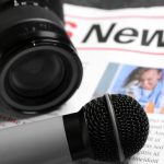 Newspaper,With,Microphone,And,Photo,Camera,On,Dark,Background,,Closeup